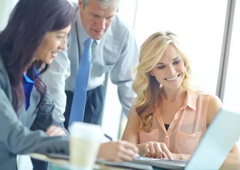 Business team collaborating around laptop screen business directory